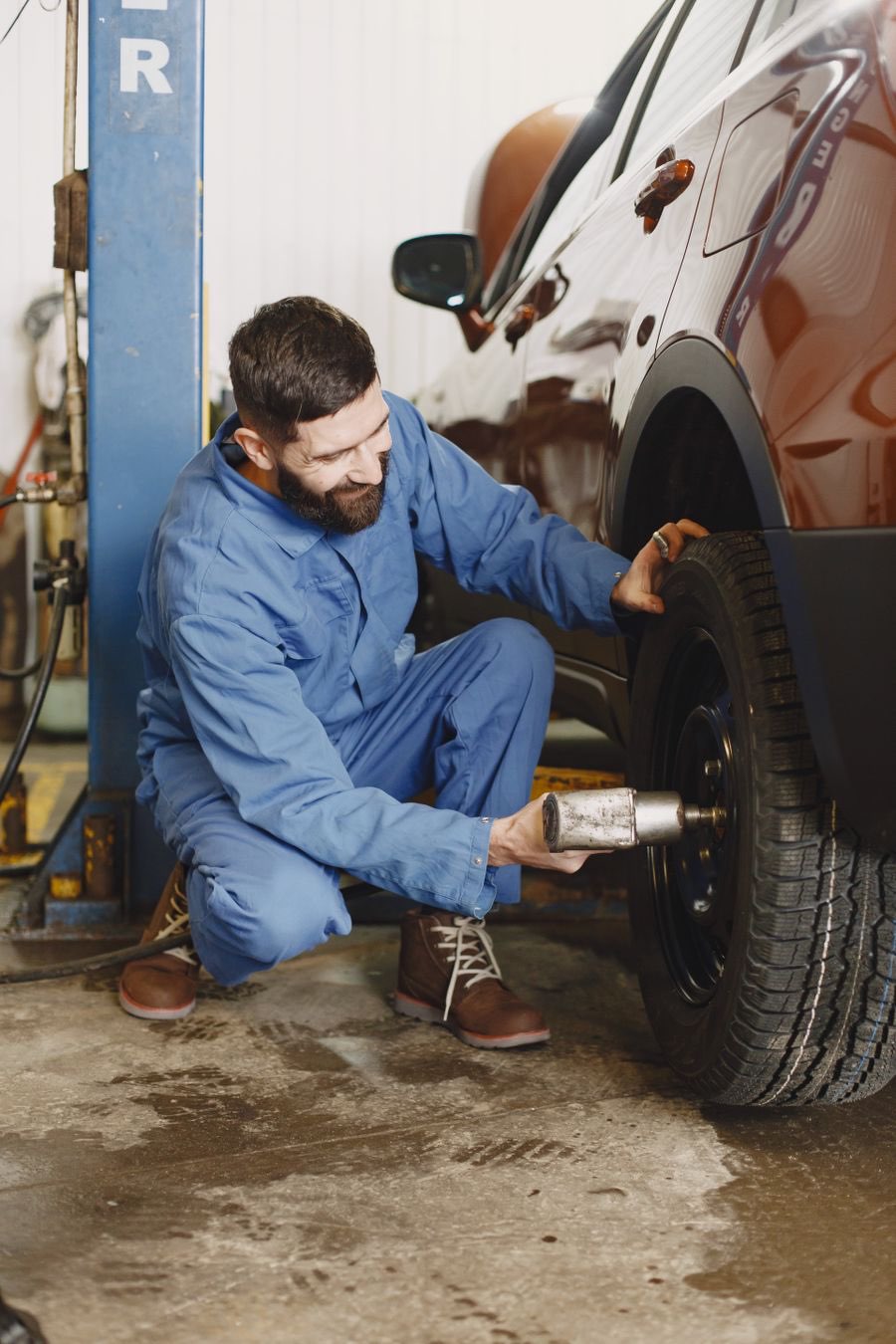 Mechanic tightening wheel lugs with an impact wrench