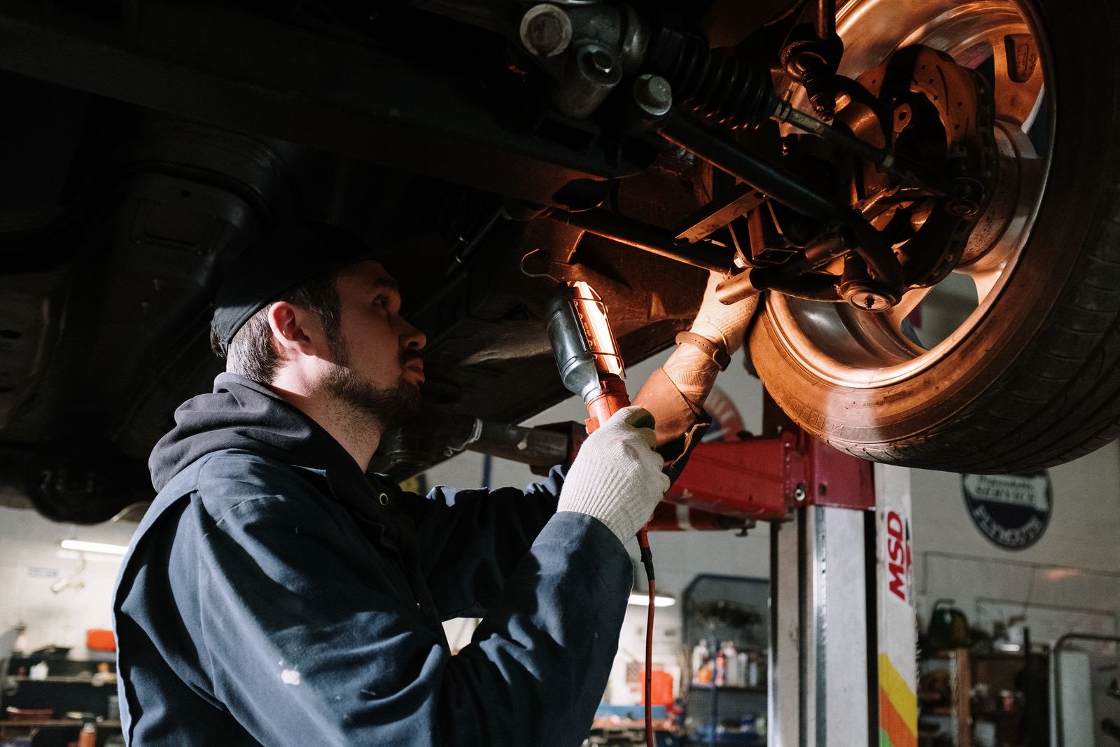 Mechanic inspecting the underside of a car with a work light