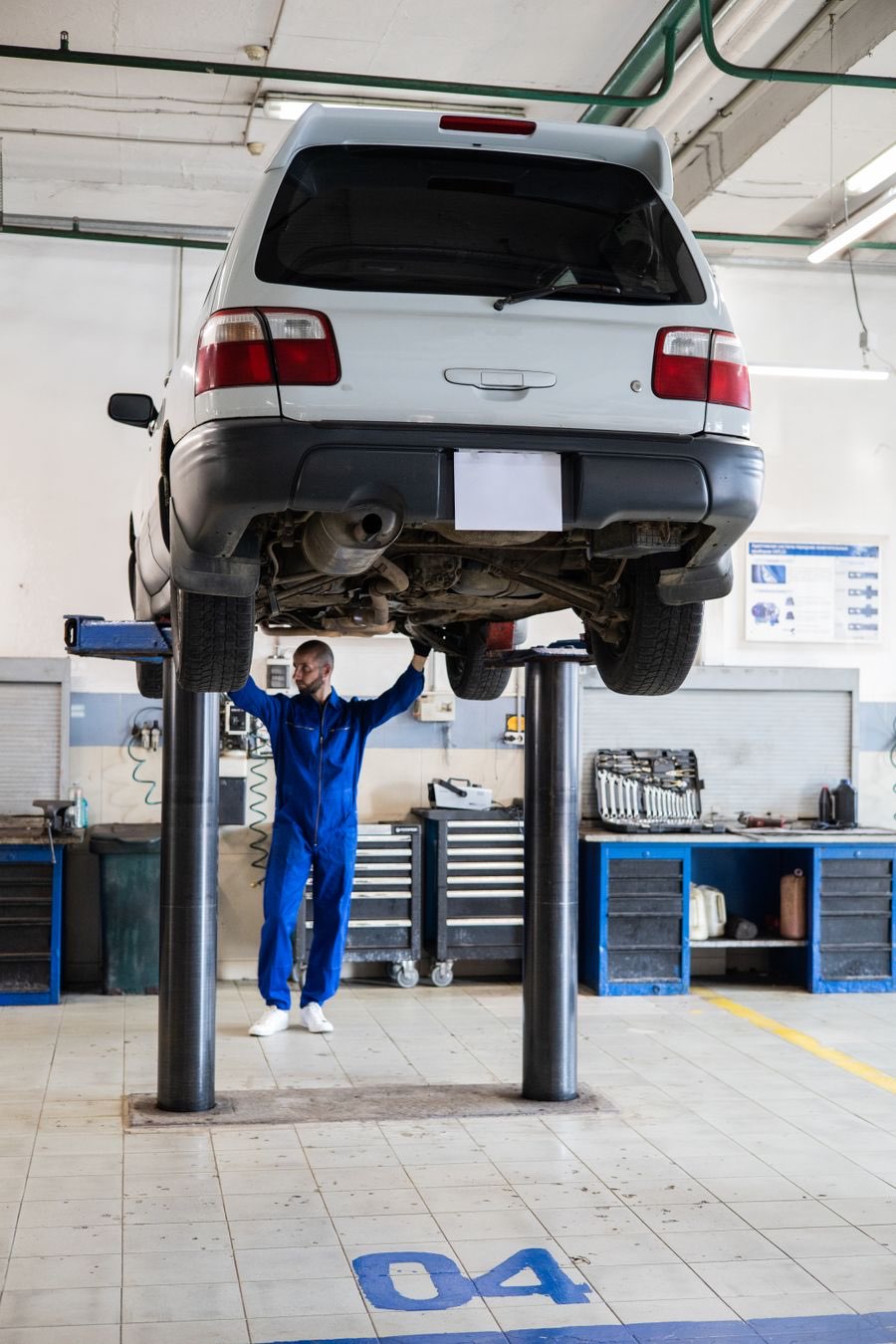 Mechanic standing under a car raised on a two-post lift