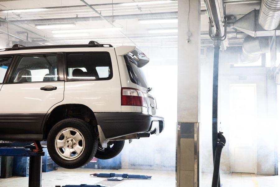 White SUV raised on a lift inside a service garage